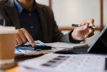 Close up of businessman working on calculator to calculate financial data report, accountancy document and laptop computer at office, business concept.