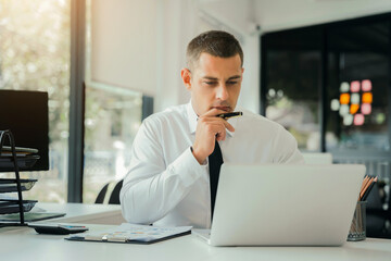 Naklejka premium pleasant looking successful professional male business accountant learns clients case, works on modern laptop and smartphone.