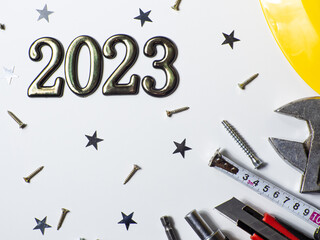 2023 with construction tools, hard hat on white background with small stars and copy space. New Year and Christmas construction greeting card. For advertising or web design. Repair home at Christmas.