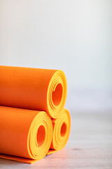 orange rolled up yoga and gymnastics mats on the floor.