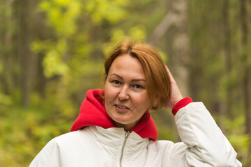 woman in a white jacket and a red hood on the background of the forest.