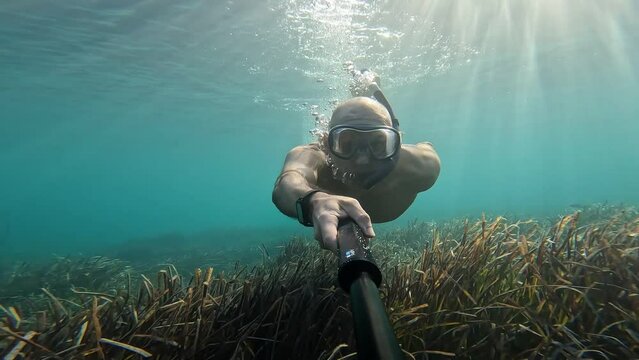 young man snorkeling in crystal clears waters of the ocean. View from camera. Concept of self portrait holiday beach and summer