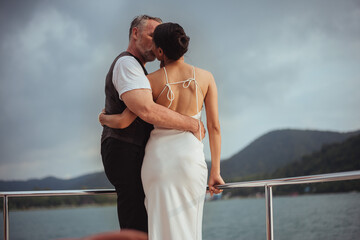 Romantic couple love hugging and kissing on yacht. Happy man and woman standing and hugging in cruise ship while sunset on vacation. luxury and honeymoon lifestyle, Happy aniversary.
