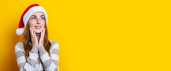 Pensive young woman holding her hands on her chin on a yellow background. Banner