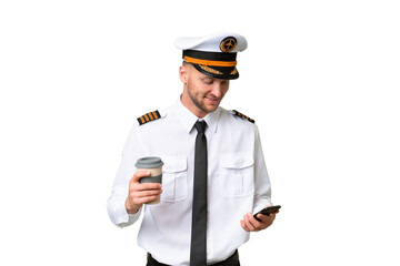 Airplane pilot man over isolated background holding coffee to take away and a mobile