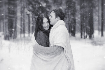 A loving couple on a winter walk. Man and woman on a date in the park in winter. Friends in a winter park