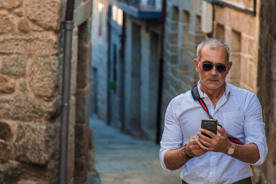 tourist mature man with phone through the streets of the town