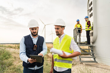 Professional team of engineer and electrical technicians working in wind turbine electricity farm, planing renewable green energy project