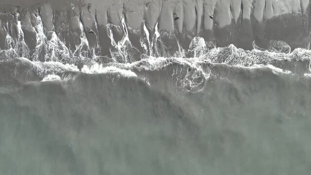 Overhead Slow Motion Drone Shot Of White Surf Patterns Washing Over Black Sand Beach, Iceland. Log profile