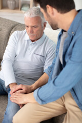 young man sitting on a sofa talking tp his grandfather