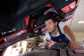 young male mechanic inspecting industrial vehicle with torch