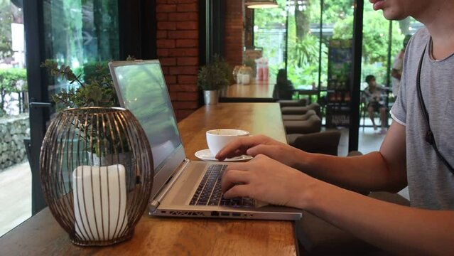 A male freelancer works on a laptop in a cafe.