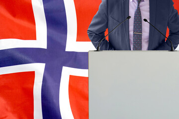 Tribune with microphone and man in suit on Norway flag background. Businessman and tribune on Norway flag background. Politician at the podium with microphones background Norway flag. Conference