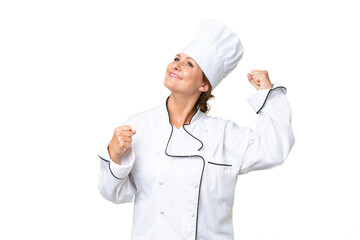 Middle-aged chef woman over isolated background celebrating a victory