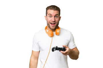 Young handsome man playing with a video game controller isolated on green chroma background with surprise and shocked facial expression © luismolinero