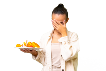 Young Arab woman holding waffles over isolated background with tired and sick expression