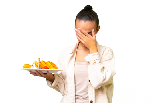 Young Arab woman holding waffles over isolated background with tired and sick expression