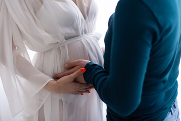 A pregnant woman's stomach is held by male hands