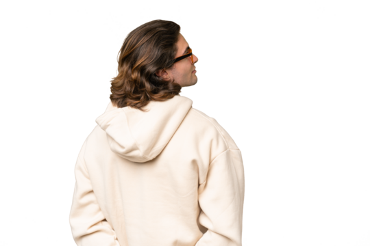 Young caucasian man isolated on green chroma background in back position and looking back