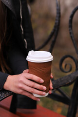 Fototapeta na wymiar cup with coffee in female hands, street photo, fast food concept. Vertical Orientation