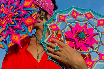 A woman holds in her hands a mandala made of multi-colored threads. Boho style clothes. On the...