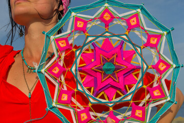 A woman holds in her hands a mandala made of multi-colored threads. Boho style clothes. On the...