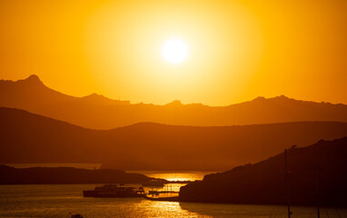 The Sun Falling Behind Mountain peak with sea foreground. A Spectacular golden Sunset 