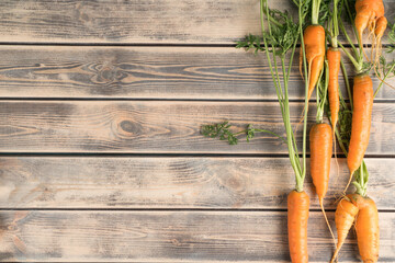 Vertical line of fresh ripe carrots on faded wooden table, top view. Raw vegetables arranged in...