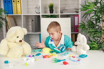 A boy with Down syndrome plays with toys on the table, early development and education of children,...