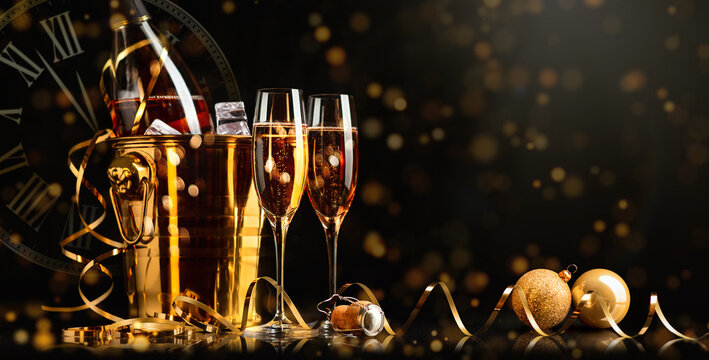Happy New Year! Golden Bucket with champagne, two glasses and a golden serpentine on a black background.