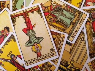 Picture of The Hanged Man tarot card from the original Rider Waite tarot deck with mixed tarot cards in the background