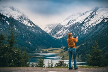 Woman taking a picture of snowy beautiful mountains