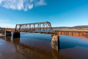 View of a rusty bridge connecting the riverbanks under the blue sky