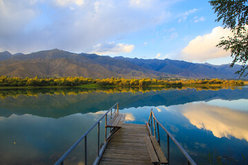 Lake in the mountains. Old wooden pier for fishing. Beautiful nature, reflection of clouds and...
