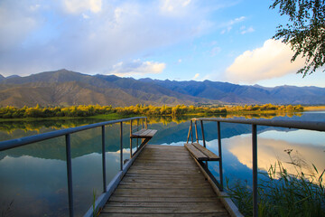 Lake in the mountains. Old wooden pier for fishing. Beautiful nature, reflection of clouds and...
