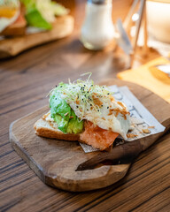 Un toast avec de l'avocat, du saumon, on oeuf et des pousses sur la table d'un restaurant