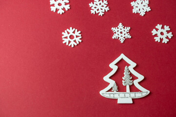 Fototapeta na wymiar small white figures of a Christmas tree on a red background with a place for text, Christmas concept, gifts,sale
