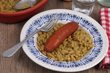 Assiette de flageolets cuisinés avec une saucisse et une fourchette en gros plan