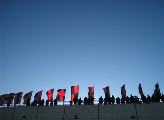 Clear blue sky with red and black flags fluttering in the wind.