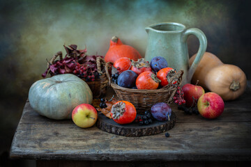 Persimmons, plums, apples and pumpkins on an old table. Autumn still life