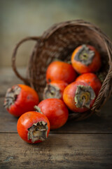 Ripe persimmon with a basket on an old table. Rustic style, selective focus