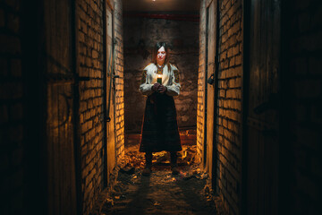 Fototapeta na wymiar A girl, a woman in traditional Ukrainian clothing stands in a dark basement with a candle in her hands. The concept of a tragedy in Ukraine, war of shelling, blackout of electricity, light. noise 