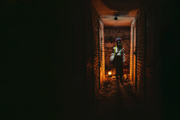 Ukrainian woman in a gas mask lights the way with an old gas lamp. Dressed in a traditional folk costume. They hide in the basement bomb shelters from chemical attacks, with poisonous gases, radiation