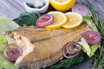 Fried golden flounder on a plate with lemon and fried onions. Restaurant serving dishes, advertising