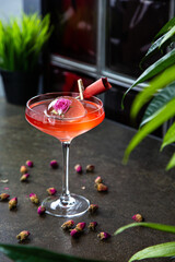 an original cocktail decorated with ice with a frozen flower. Bar pink cocktail in a martini glass. horizontal photo
