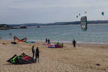 Fototapeta na wymiar Santander, Spain - 31 Oct, 2022: Kite surfers and bathers on the Playa de los Peligros beach, Santander, Cantabria