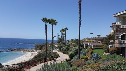 Fototapeta na wymiar California, USA. People walk on a coastline. Blue ocean and blue sky. Houses along the coastline.