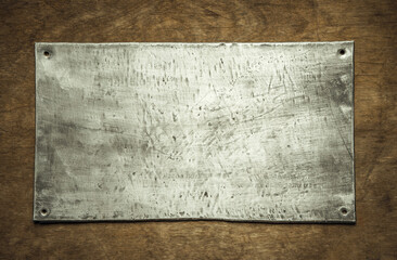Vintage iron plaque on a wooden table. An old rectangular plate made of aluminum. Industrial plate on a wooden background.
