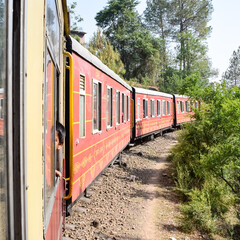 Obraz premium Toy Train moving on mountain slopes, beautiful view, one side mountain, one side valley moving on railway to the hill, among green natural forest. Toy train from Kalka to Shimla in India, Indian Train