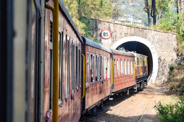 Toy Train moving on mountain slopes, beautiful view, one side mountain, one side valley moving on railway to the hill, among green natural forest. Toy train from Kalka to Shimla in India, Indian Train